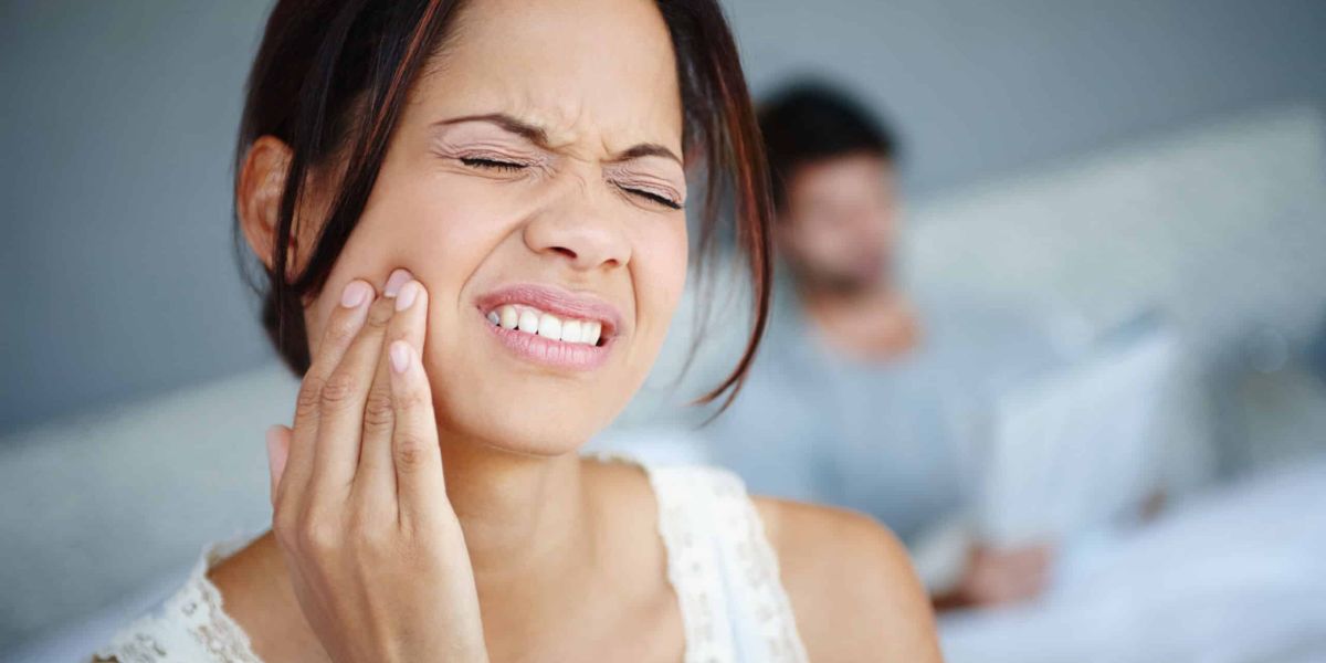Woman experiencing jaw pain due to TMJ,